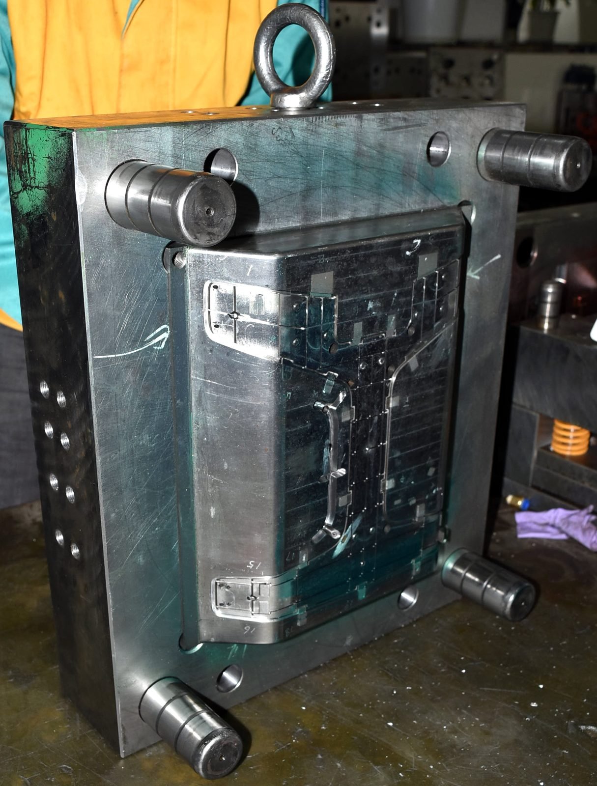 Product Design Challenges Behind the Tstand Base: Ergonomics, Sink Marks, Snap-Fits, and Lifters 18 Core-side half of the Tstand base injection mold on a workbench, with guide pins, an eye bolt, and the injection mold lifters at rest in the core