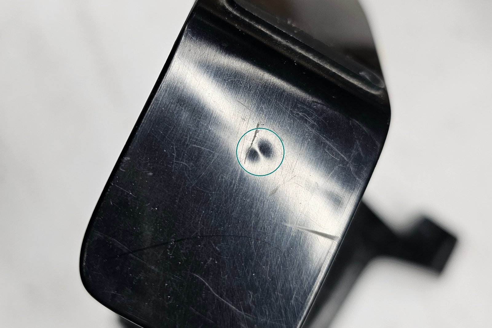 Product Design Challenges Behind the Tstand Base: Ergonomics, Sink Marks, Snap-Fits, and Lifters 7 Close-up photo of a real sink mark, a double dimple on the glossy black angled foot of an early molded Tstand base, circled in teal