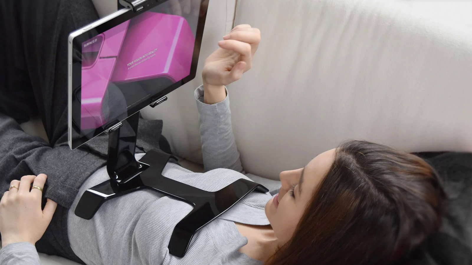 Product Design Challenges Behind the Tstand Base: Ergonomics, Sink Marks, Snap-Fits, and Lifters 1 Woman lying on a couch with the Tstand tablet stand resting on her chest, holding a tablet above her